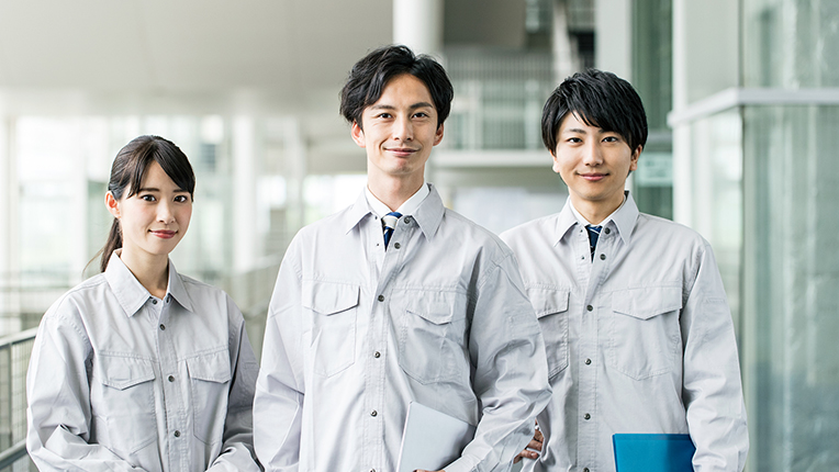 凛々しい表情でたたずむ作業着姿の男女