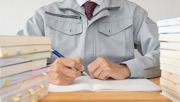 資格の勉強をする作業着姿の男性