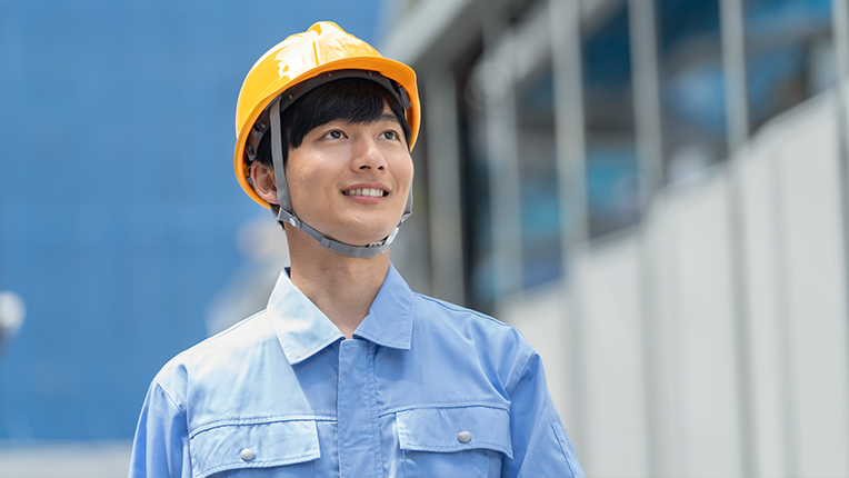 笑顔で現場を見る作業着の男性