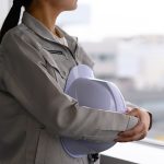 建物の中から遠くを見る作業着姿の女性