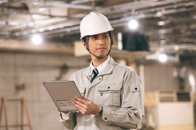 現場で確認作業をする作業着の男性のイメージ