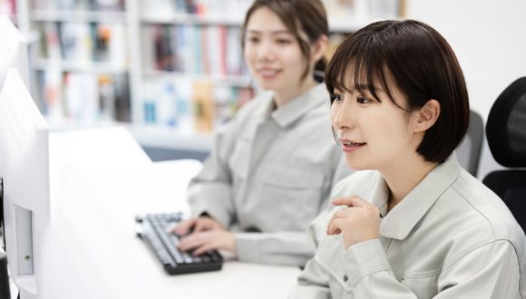作業着でパソコンを操作する女性たちのイメージ