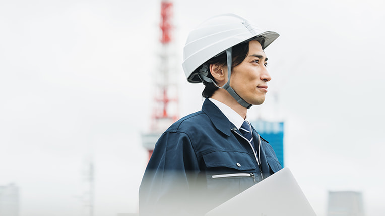 遠くを見るヘルメットをかぶった男性施工管理