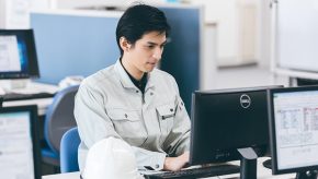 事務所でパソコン作業を行う作業着姿の男性施工管理